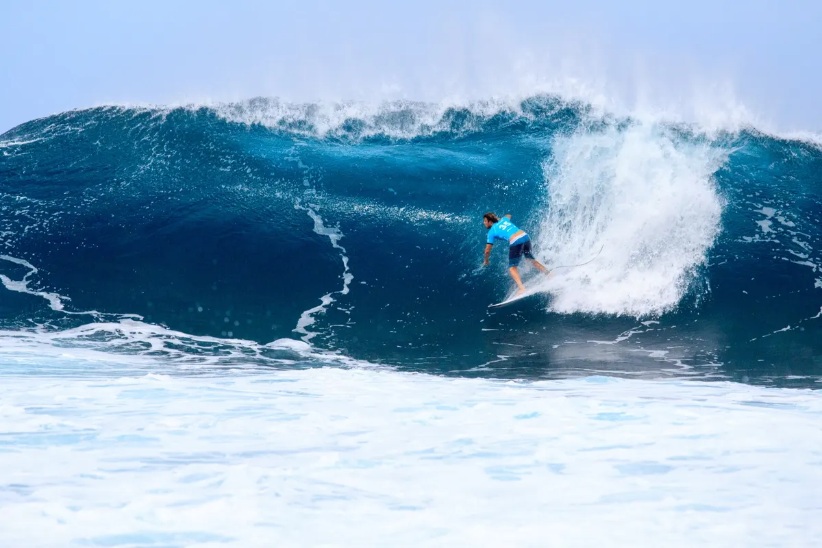 Surfer dropping in on a heavy deep blue wave